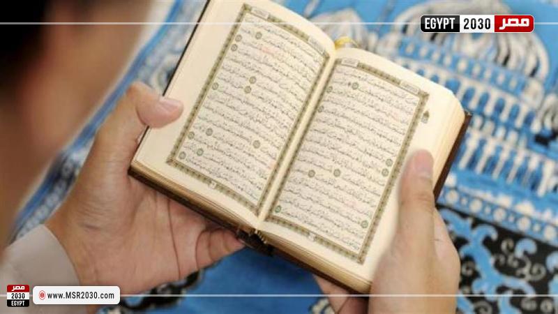 شخص يصلي ويحمل في يده المصحف الشريف