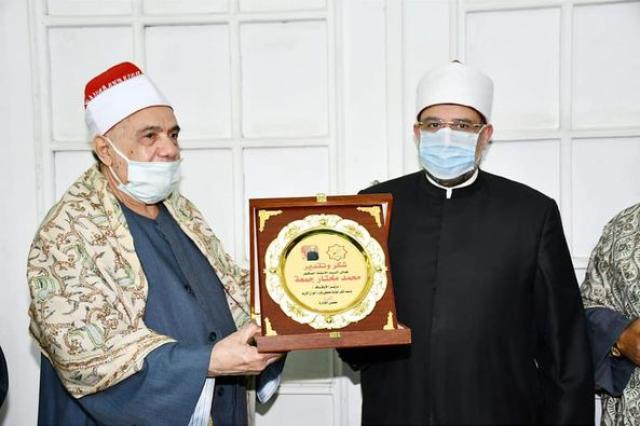 وزير الأاوقاف ونقيب القرَّاء خلال تسلمه الدرع