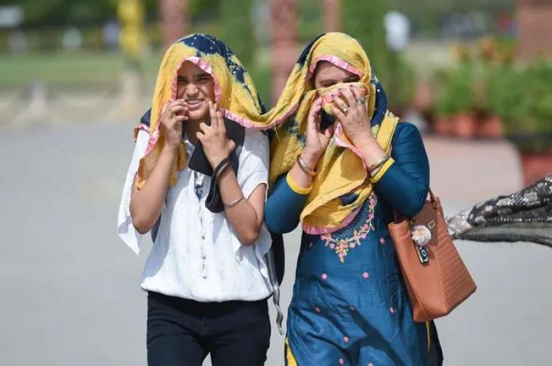 سيدتان تتشاركان الوشاح لتجنب حرارة الشمس وسط موجة حارة في نيودلهي بالهند